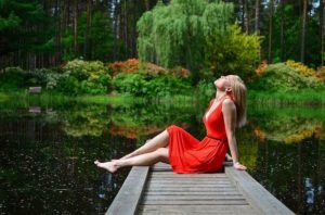 Žena v červených šatek na břehu rybníka