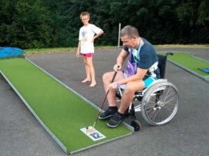 Muž na vozíku hraje minigolf
